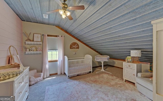 carpeted bedroom featuring ceiling fan, a crib, lofted ceiling, and wooden ceiling