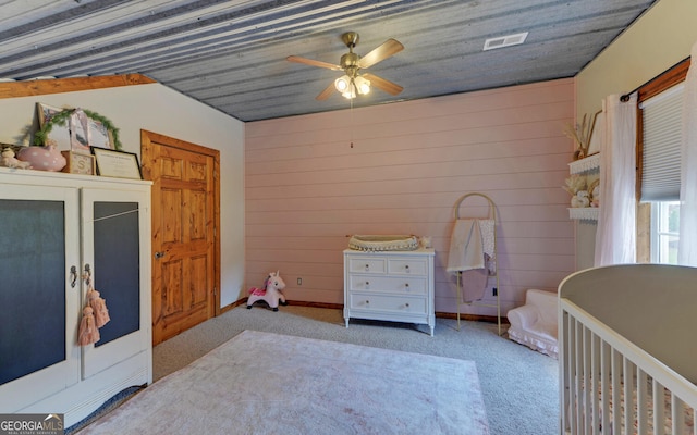 carpeted bedroom featuring vaulted ceiling, ceiling fan, and wood walls