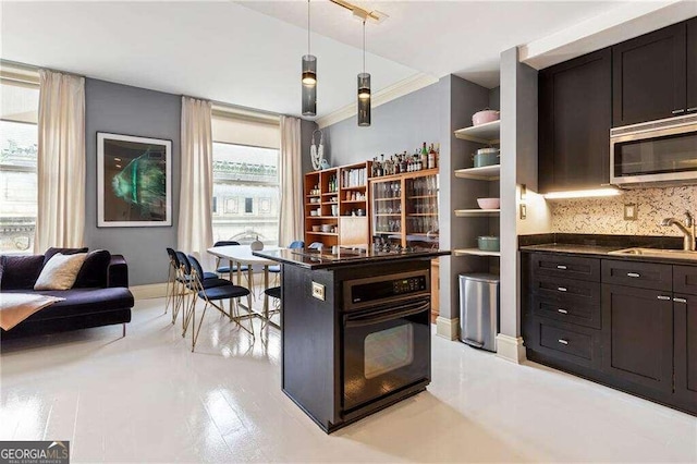 bar featuring tasteful backsplash, pendant lighting, black oven, dark brown cabinets, and sink