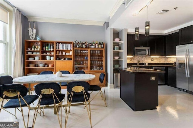 kitchen featuring appliances with stainless steel finishes, decorative backsplash, a kitchen island, pendant lighting, and crown molding