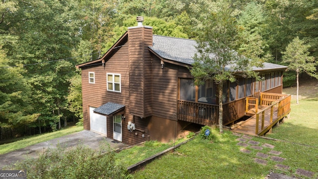 view of property exterior featuring a wooden deck, a sunroom, a lawn, and a garage