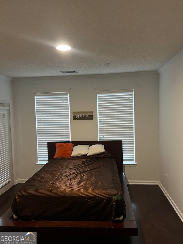 bedroom with ornamental molding, dark hardwood / wood-style flooring, and a textured ceiling