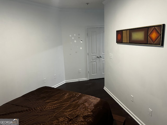 unfurnished bedroom with crown molding and dark wood-type flooring