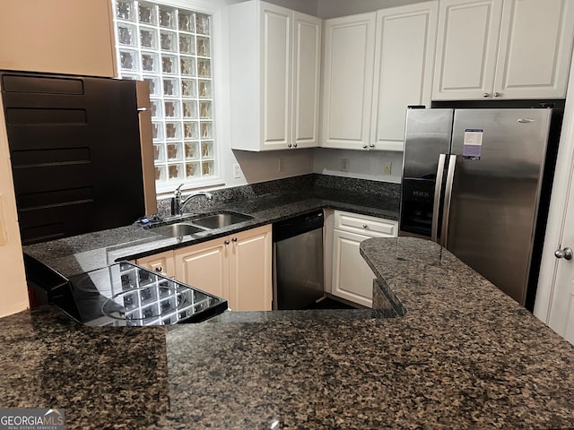 kitchen with dark stone countertops, white cabinets, appliances with stainless steel finishes, and sink