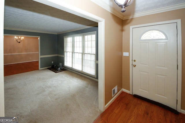 entryway featuring wood-type flooring, a notable chandelier, ornamental molding, and a healthy amount of sunlight