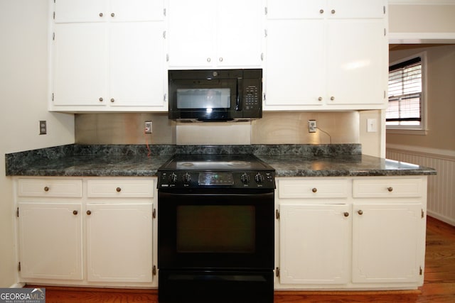 kitchen featuring white cabinets, wooden walls, hardwood / wood-style floors, and black appliances