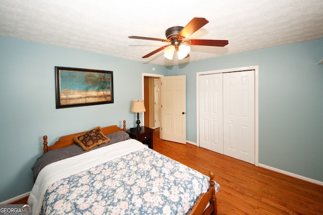 bedroom with a closet, hardwood / wood-style floors, a textured ceiling, and ceiling fan