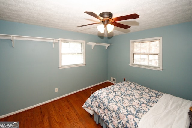 bedroom with ceiling fan, hardwood / wood-style flooring, and a textured ceiling