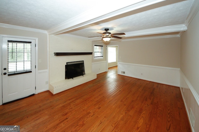 unfurnished living room featuring wood-type flooring, plenty of natural light, and crown molding