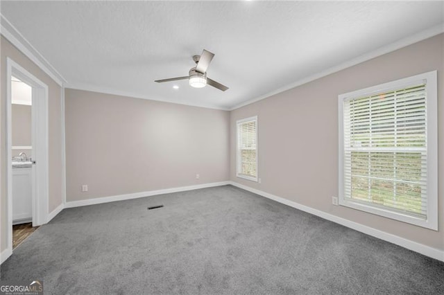 spare room with ceiling fan, crown molding, carpet, and a healthy amount of sunlight