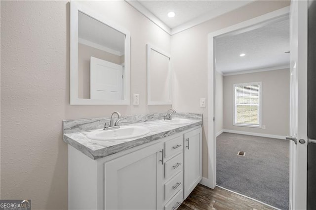 bathroom featuring a textured ceiling, ornamental molding, vanity, and hardwood / wood-style flooring