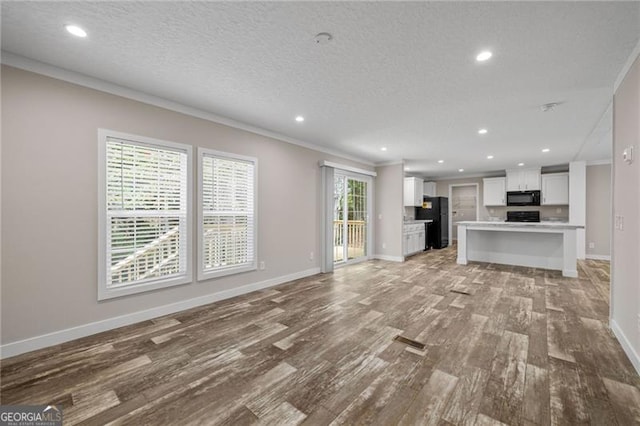 unfurnished living room with a textured ceiling, crown molding, light hardwood / wood-style floors, and a healthy amount of sunlight