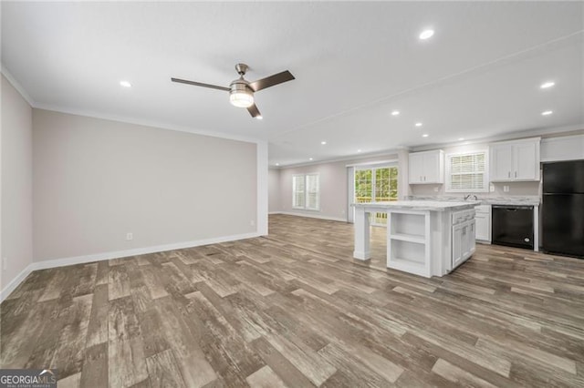 kitchen with white cabinets, ornamental molding, a kitchen island, light hardwood / wood-style flooring, and black appliances