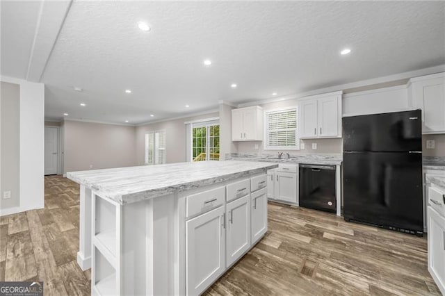 kitchen featuring white cabinetry, a kitchen island, black appliances, crown molding, and hardwood / wood-style floors