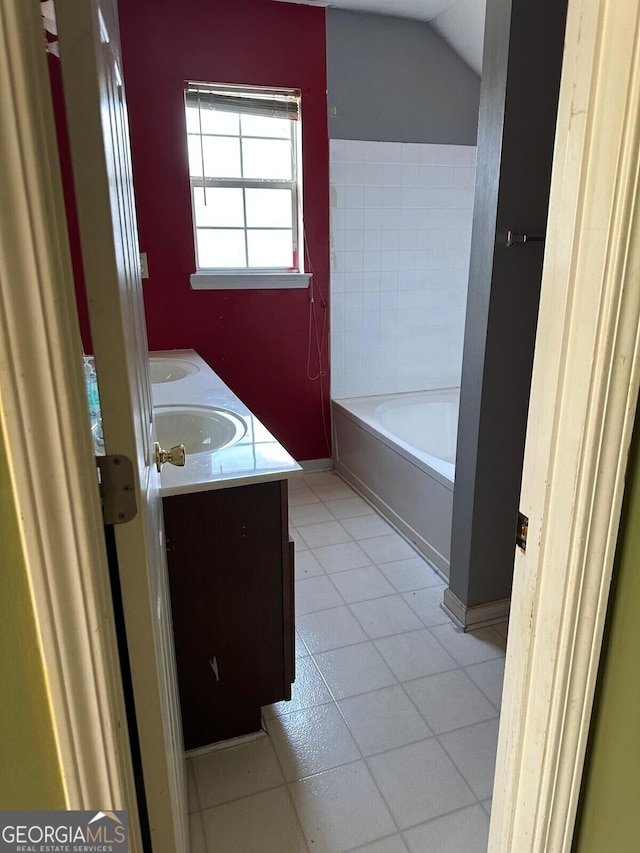 bathroom featuring vanity, a bathtub, tile patterned flooring, and lofted ceiling