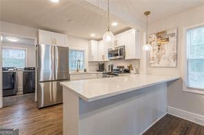 kitchen featuring kitchen peninsula, stainless steel appliances, and white cabinets