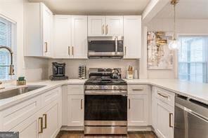 kitchen featuring white cabinets, stainless steel appliances, sink, and decorative light fixtures