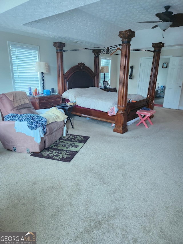 bedroom featuring ceiling fan, a textured ceiling, ornate columns, and carpet flooring