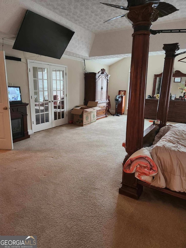 carpeted bedroom with a textured ceiling, ornate columns, vaulted ceiling, french doors, and access to outside