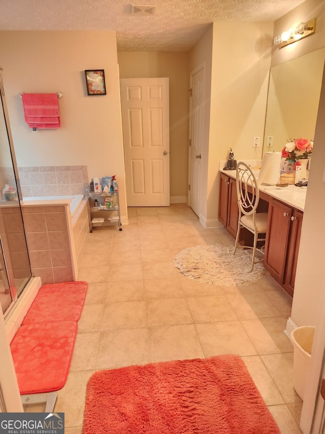 full bath with a textured ceiling, vanity, tile patterned flooring, a shower with door, and a garden tub