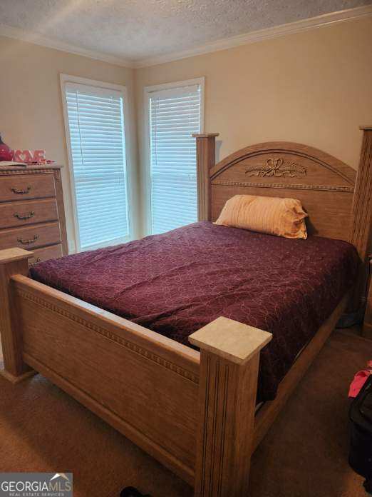 bedroom featuring carpet flooring, a textured ceiling, and crown molding