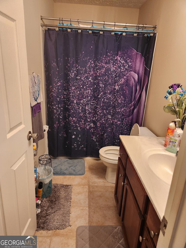 bathroom featuring tile patterned flooring, vanity, a textured ceiling, and toilet