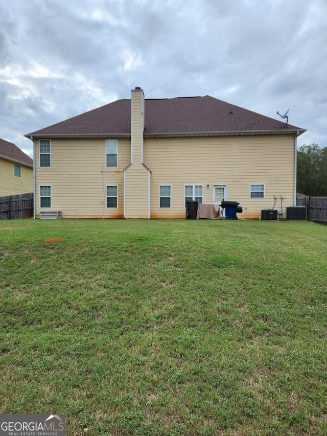 rear view of property featuring fence and a lawn