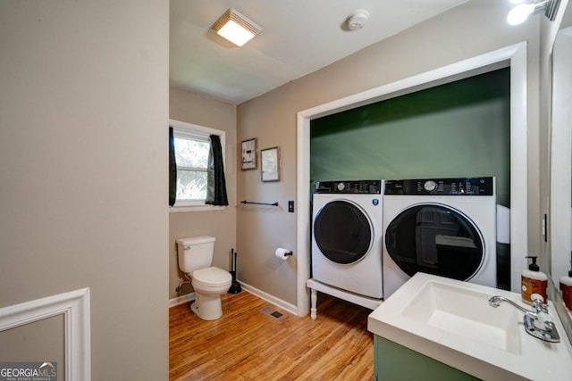 laundry area featuring light wood-type flooring, sink, and washing machine and clothes dryer