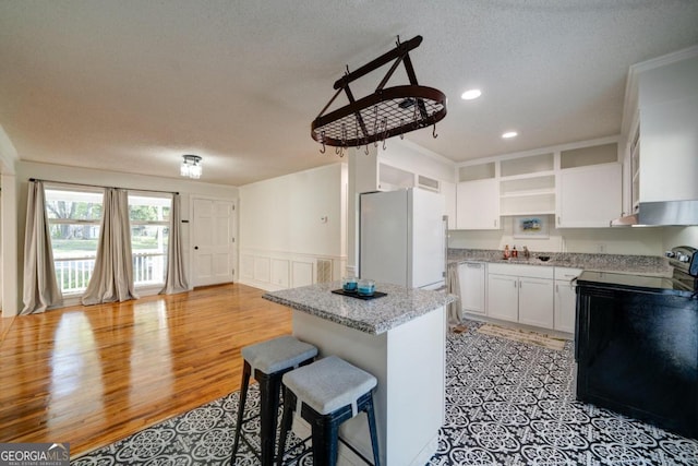 kitchen with light wood-type flooring, white refrigerator, a textured ceiling, sink, and white cabinets