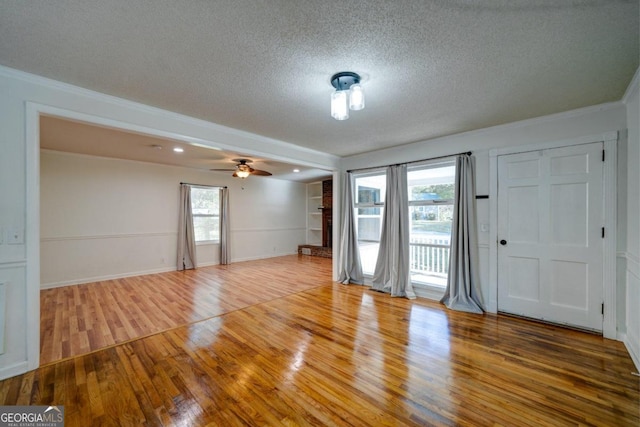 spare room featuring a textured ceiling, hardwood / wood-style flooring, ceiling fan, and crown molding