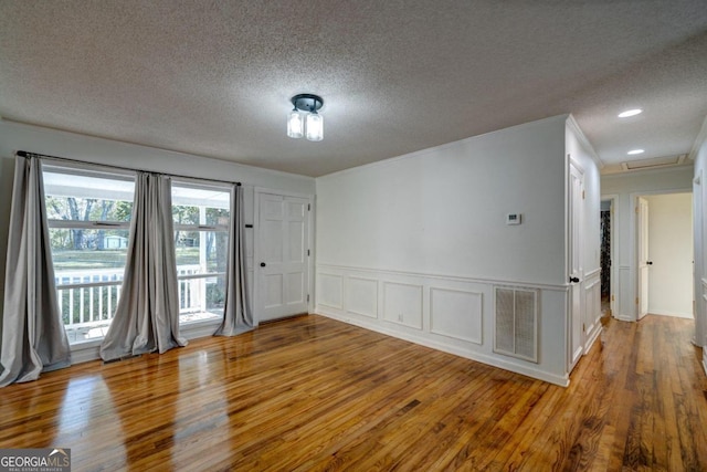 unfurnished room with a textured ceiling, ornamental molding, and hardwood / wood-style floors