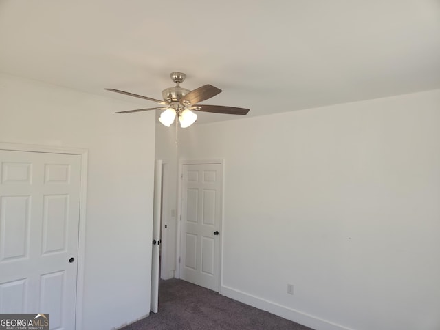 unfurnished bedroom featuring dark colored carpet, a ceiling fan, and baseboards