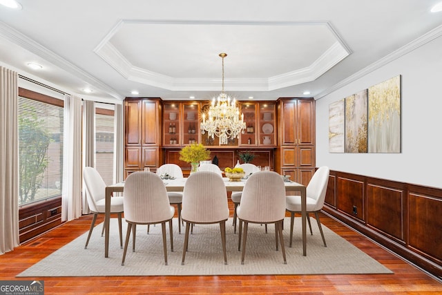 dining space featuring an inviting chandelier, a tray ceiling, hardwood / wood-style flooring, and crown molding