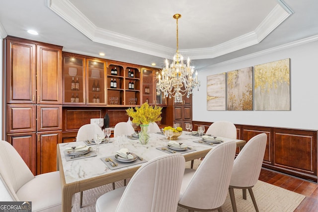 dining space featuring wood-type flooring, crown molding, and a raised ceiling