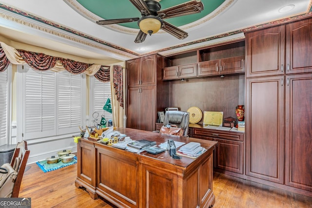 home office featuring light hardwood / wood-style flooring, a tray ceiling, and ceiling fan