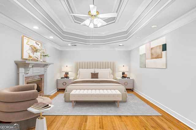 bedroom with light hardwood / wood-style flooring, ceiling fan, a raised ceiling, and crown molding