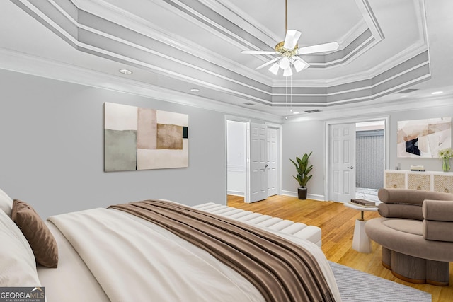 bedroom with wood-type flooring, a tray ceiling, and crown molding