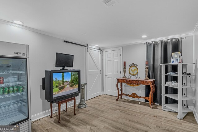 interior space featuring light hardwood / wood-style flooring, crown molding, and a barn door