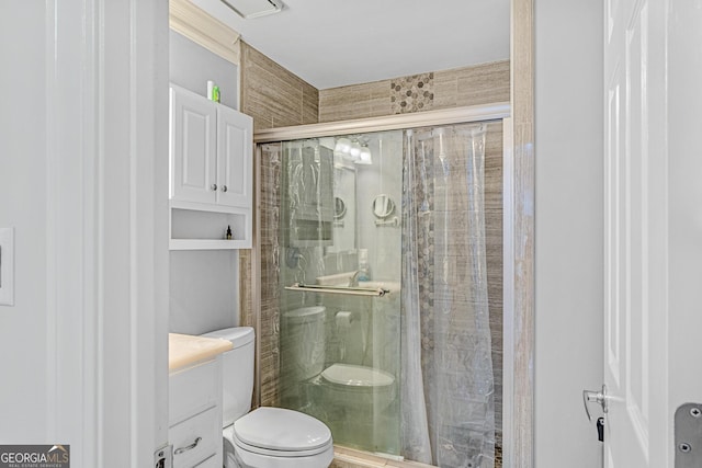 bathroom with a shower with door, vanity, and toilet