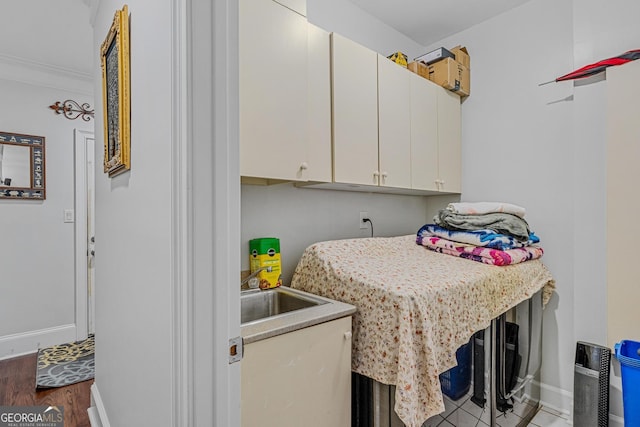 laundry room featuring ornamental molding, hardwood / wood-style flooring, cabinets, and sink