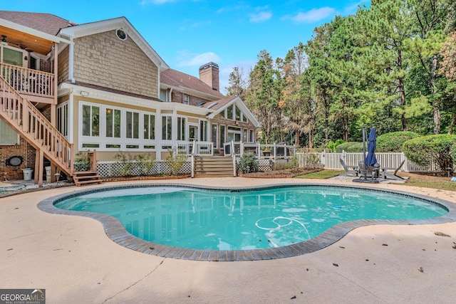 view of swimming pool with a deck, a sunroom, and a patio area