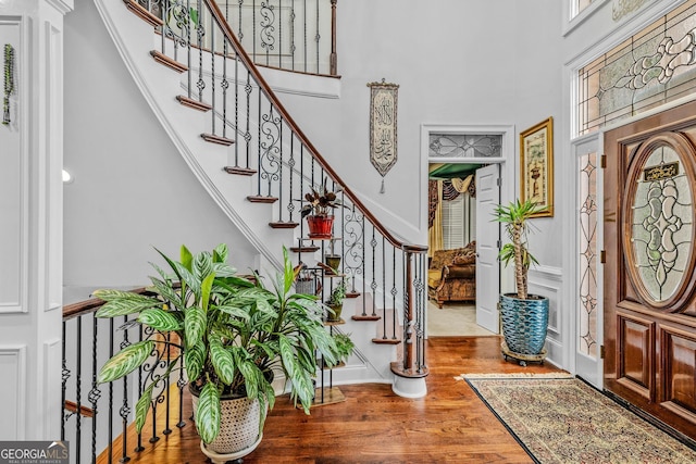 foyer entrance featuring a towering ceiling and hardwood / wood-style floors