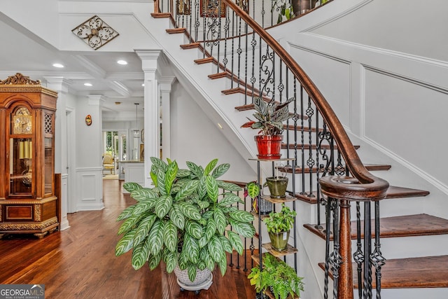 staircase with coffered ceiling, beam ceiling, hardwood / wood-style flooring, decorative columns, and ornamental molding