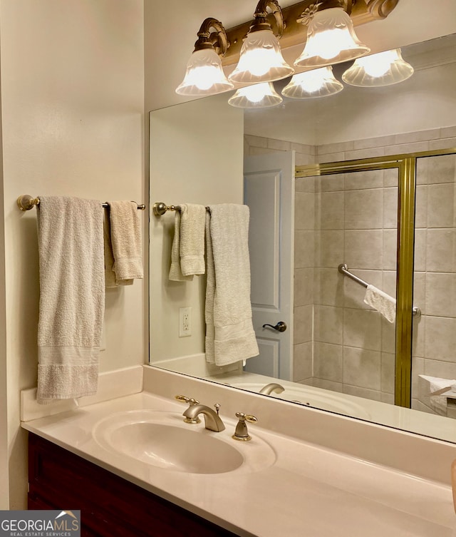 bathroom featuring a shower with door and vanity