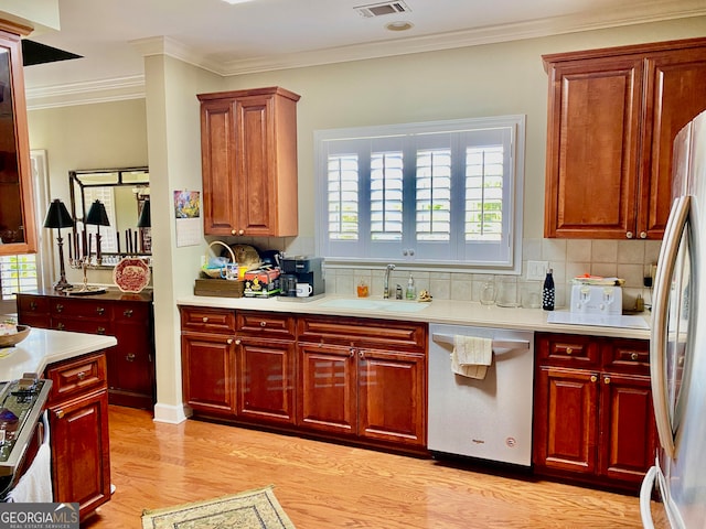 kitchen featuring appliances with stainless steel finishes, light wood-type flooring, sink, and a healthy amount of sunlight