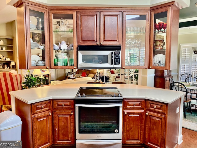 kitchen with stainless steel appliances, crown molding, light hardwood / wood-style floors, and kitchen peninsula