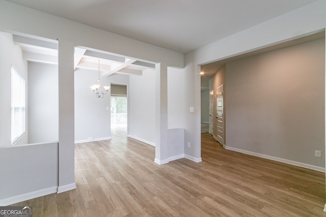 spare room with hardwood / wood-style floors, a notable chandelier, beam ceiling, and coffered ceiling