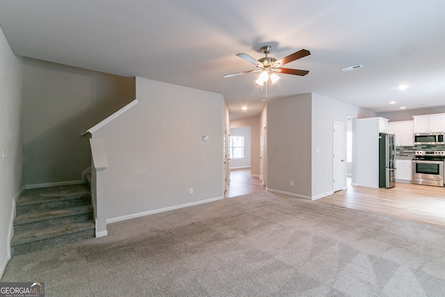 unfurnished living room with ceiling fan and light colored carpet