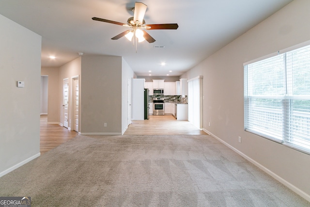 unfurnished living room with ceiling fan and light colored carpet