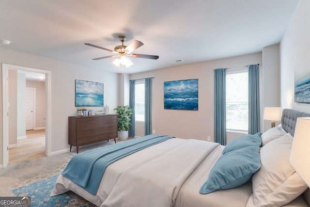 carpeted bedroom with multiple windows and ceiling fan